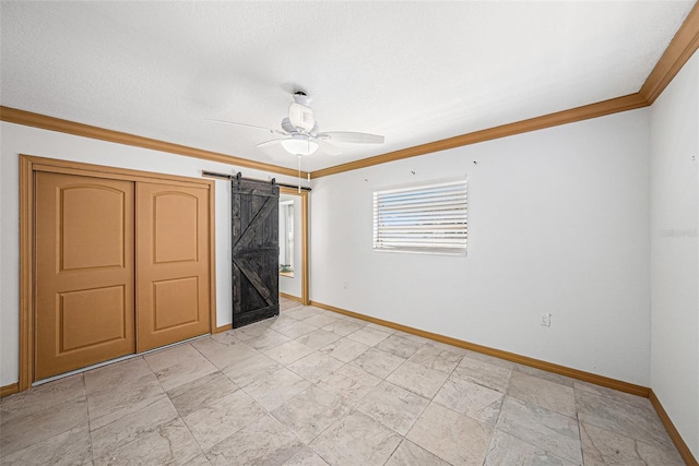 unfurnished bedroom featuring a barn door, baseboards, a ceiling fan, ornamental molding, and a textured ceiling