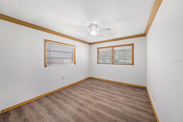 spare room featuring a textured ceiling, baseboards, wood finished floors, and crown molding