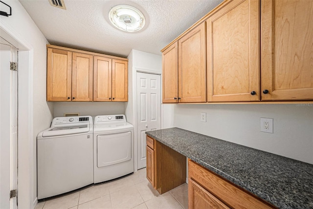 laundry area with cabinet space, visible vents, washing machine and clothes dryer, a textured ceiling, and light tile patterned flooring