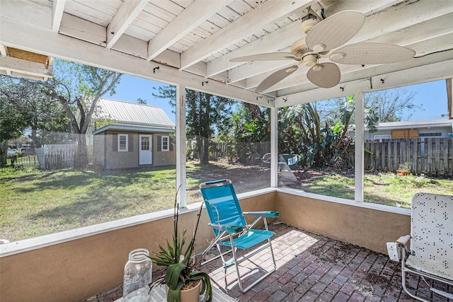 unfurnished sunroom featuring beam ceiling and ceiling fan