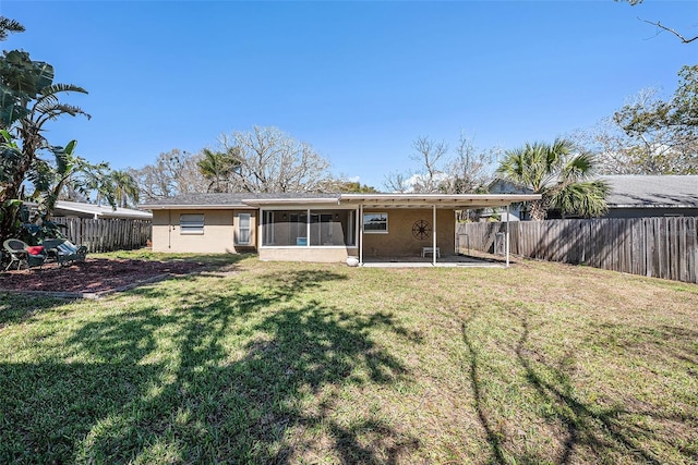 back of property featuring a sunroom, a fenced backyard, a lawn, and stucco siding