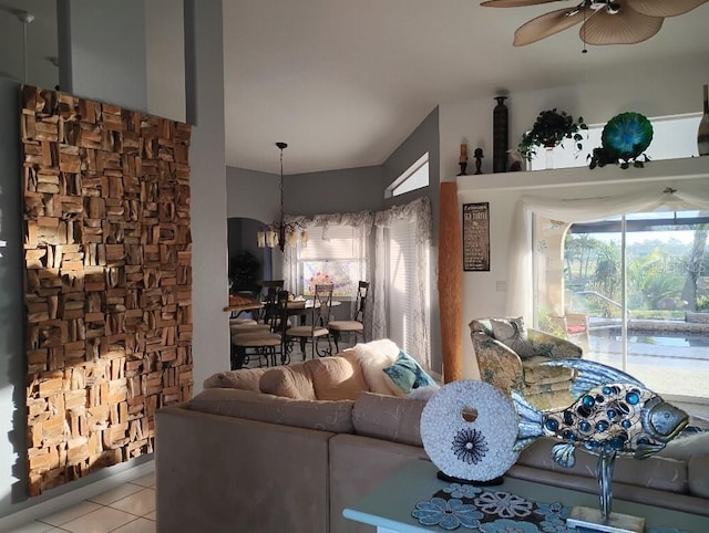 living area with light tile patterned floors, vaulted ceiling, and ceiling fan with notable chandelier