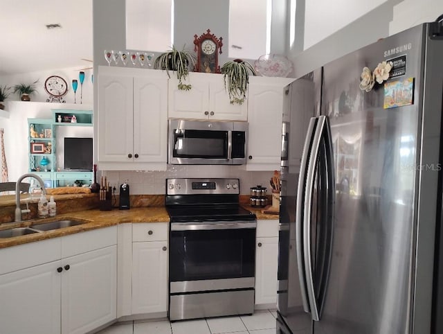 kitchen featuring stainless steel appliances, light stone counters, a sink, and white cabinets