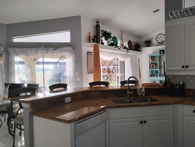 kitchen with visible vents, dishwasher, dark stone countertops, white cabinetry, and a sink