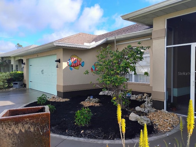 view of side of property with concrete driveway, an attached garage, and stucco siding