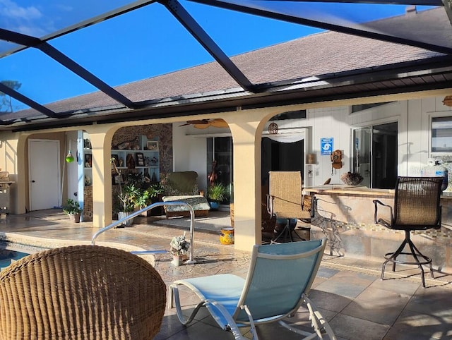 view of patio with outdoor dry bar, glass enclosure, and a ceiling fan