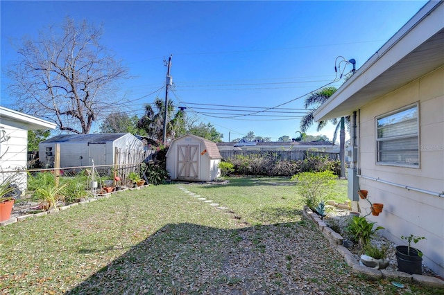 view of yard featuring fence, a storage unit, and an outdoor structure