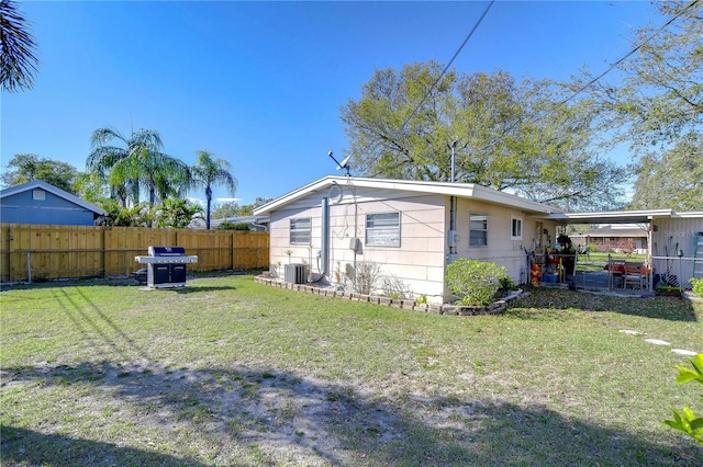 back of property featuring a yard, central AC unit, and fence