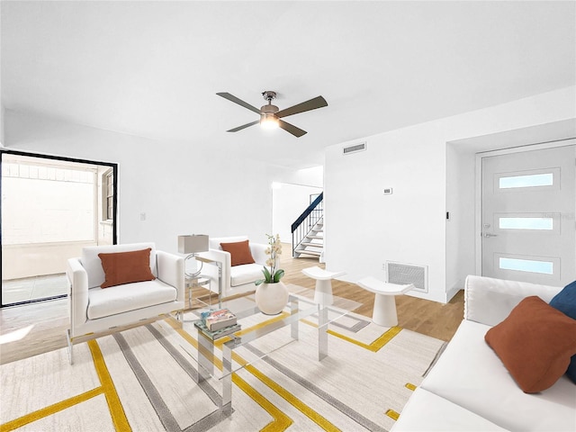 living room featuring a healthy amount of sunlight, stairs, visible vents, and wood finished floors