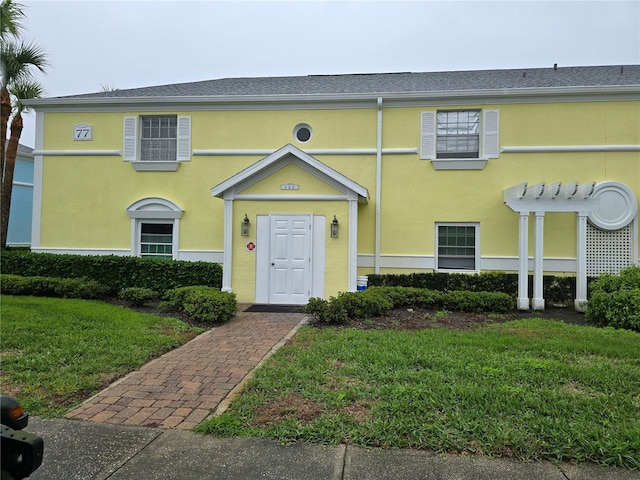 view of property featuring a front lawn and stucco siding