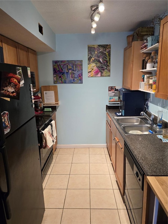 kitchen featuring light tile patterned floors, dark countertops, a textured ceiling, black appliances, and a sink