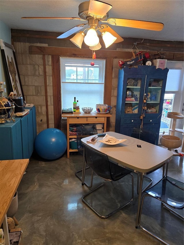 dining space with concrete floors and a ceiling fan