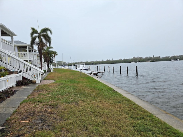 dock area with a water view, stairway, and a lawn