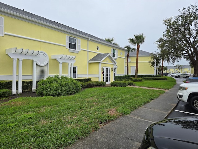 view of front of property with a front lawn, a pergola, and stucco siding