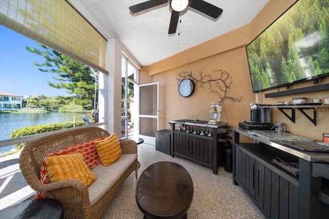 sunroom featuring a water view and a ceiling fan