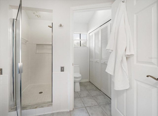 full bath with a stall shower, a closet, toilet, and tile patterned floors