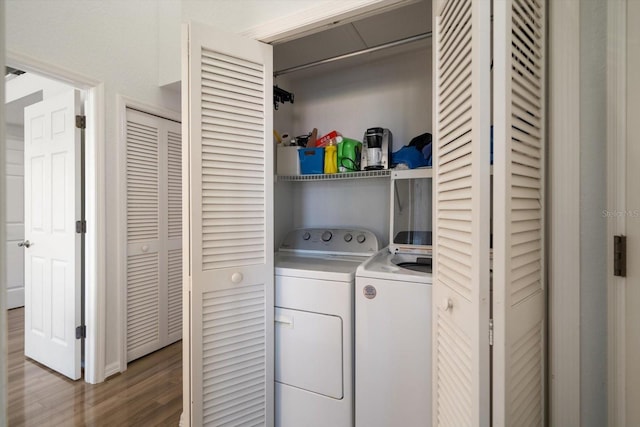 clothes washing area with laundry area, washer and clothes dryer, and wood finished floors