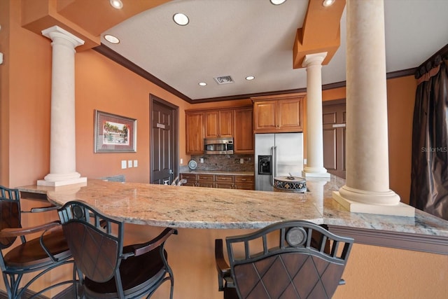 kitchen featuring appliances with stainless steel finishes, decorative columns, and a peninsula