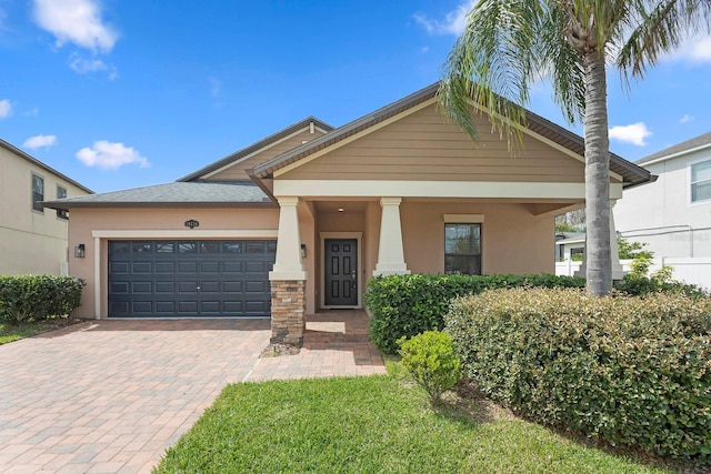 view of front of home featuring decorative driveway, an attached garage, and stucco siding