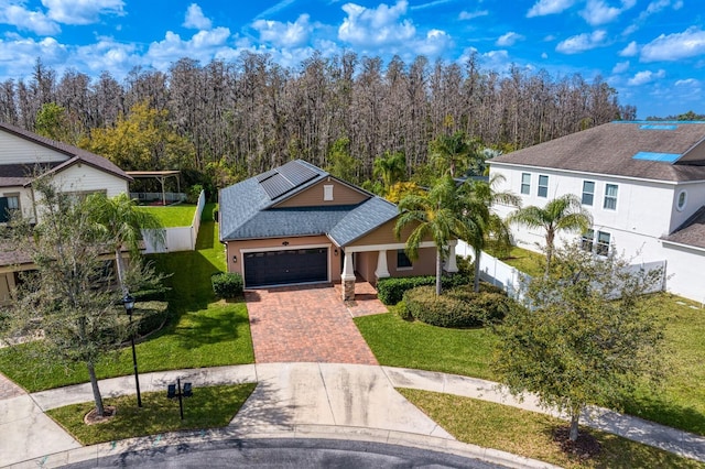 view of front of property with roof with shingles, an attached garage, fence, decorative driveway, and a front yard