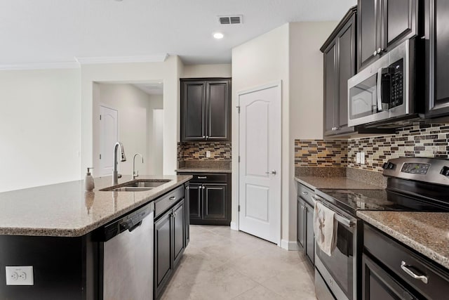 kitchen with a center island with sink, visible vents, light stone countertops, stainless steel appliances, and a sink