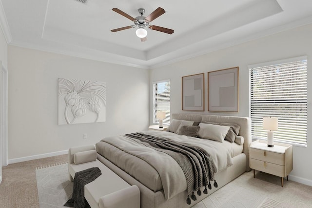 bedroom featuring baseboards, a raised ceiling, and light colored carpet