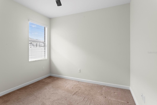 carpeted empty room featuring a ceiling fan and baseboards