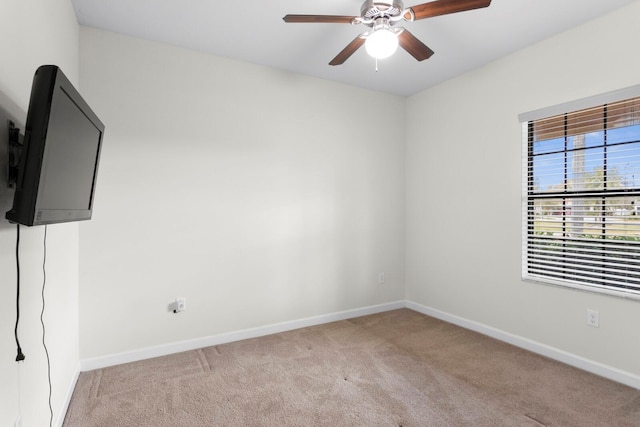 spare room with light carpet, a ceiling fan, and baseboards