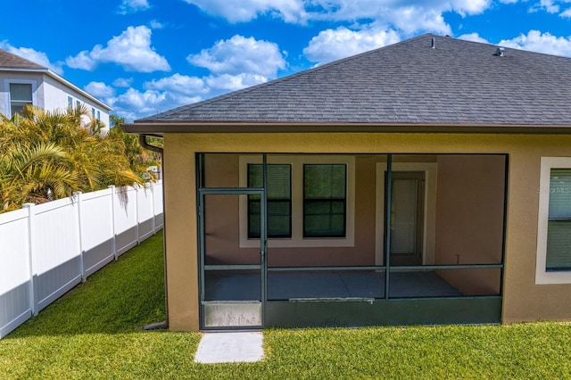 rear view of property with a shingled roof, a lawn, fence, and a sunroom