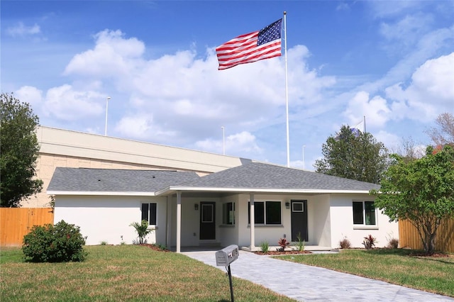 ranch-style house featuring a front yard, fence, and stucco siding