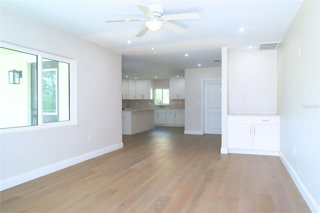 unfurnished living room with a ceiling fan, light wood-style flooring, visible vents, and baseboards