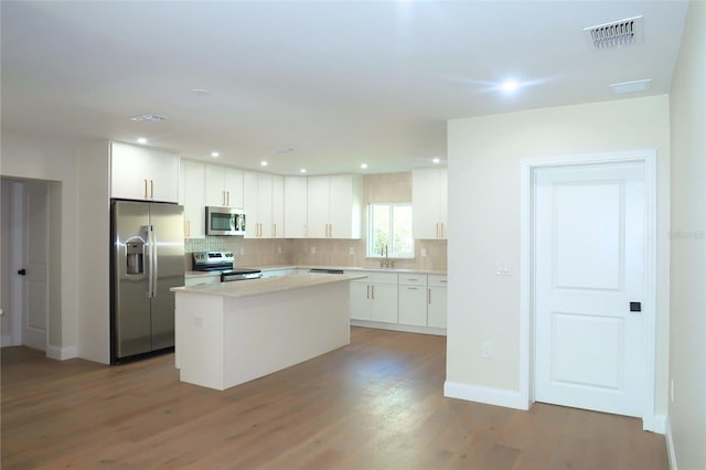 kitchen featuring visible vents, decorative backsplash, appliances with stainless steel finishes, white cabinetry, and a sink