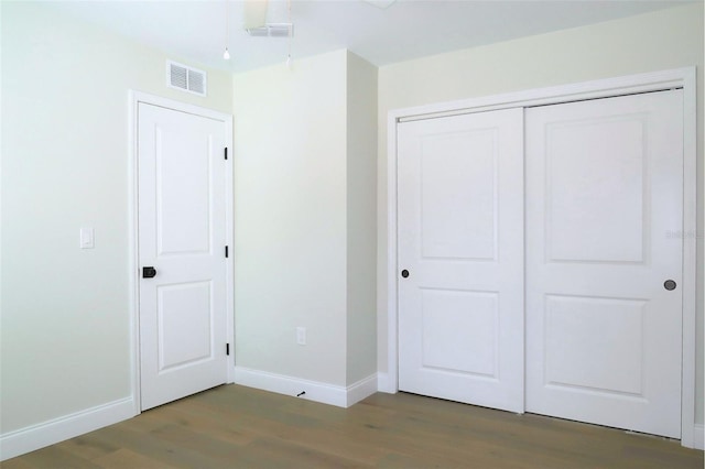 unfurnished bedroom featuring baseboards, visible vents, and wood finished floors