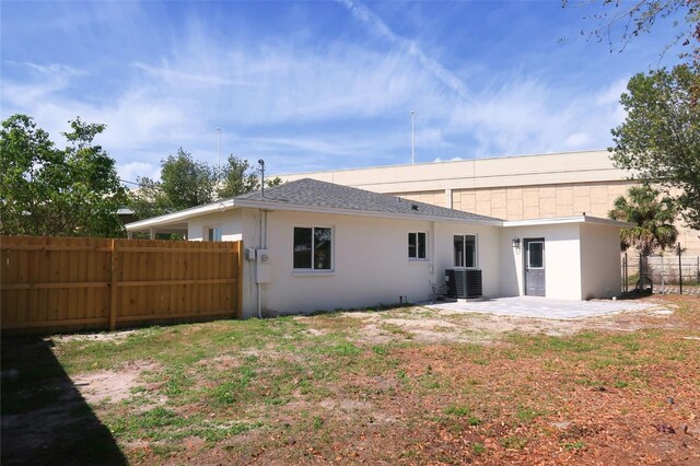 rear view of house featuring a patio area, fence, central AC, and stucco siding