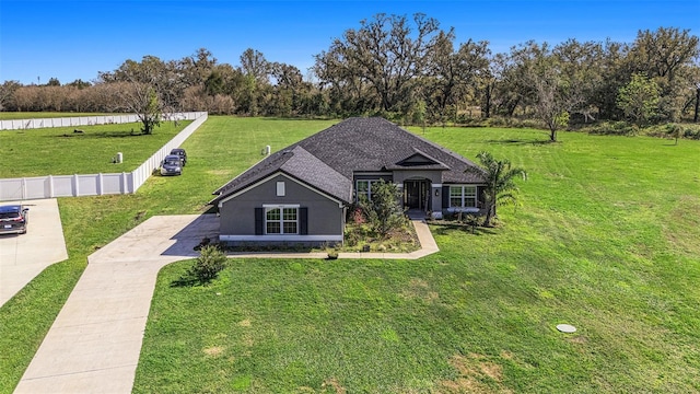 view of front of property with roof with shingles, a front yard, and fence