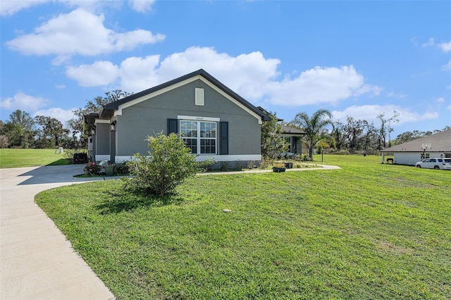 view of side of property with a yard, driveway, and stucco siding