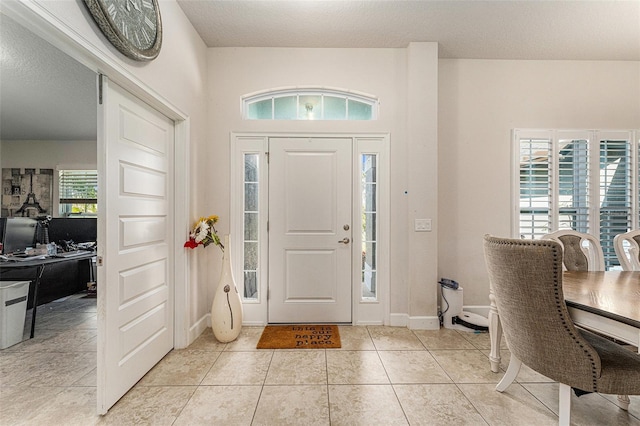 entrance foyer with light tile patterned flooring, a textured ceiling, and baseboards