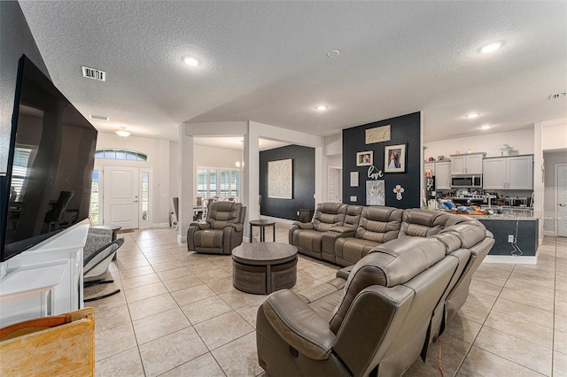 living room featuring light tile patterned floors, a textured ceiling, visible vents, and recessed lighting