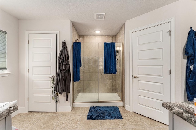 full bath featuring visible vents, a shower stall, a textured ceiling, tile patterned flooring, and baseboards