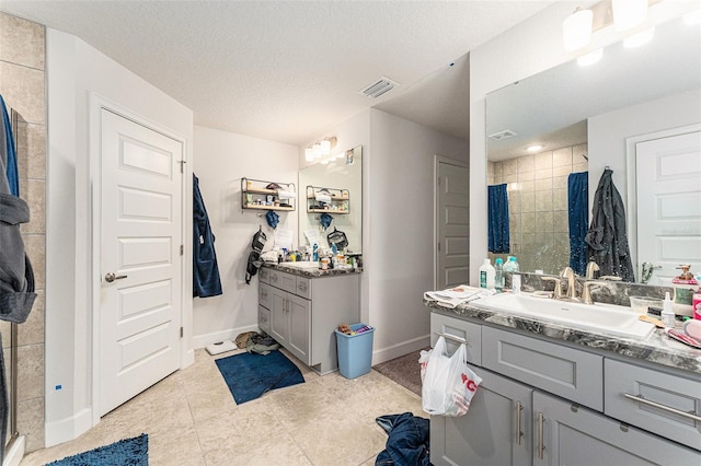 full bath featuring visible vents, a stall shower, a sink, a textured ceiling, and baseboards