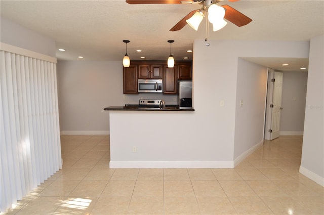 kitchen with light tile patterned floors, stainless steel appliances, dark countertops, and ceiling fan