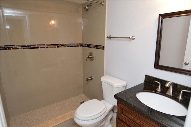 bathroom with vanity, toilet, and a tile shower