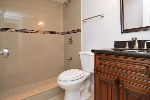 bathroom featuring toilet, vanity, and a tile shower