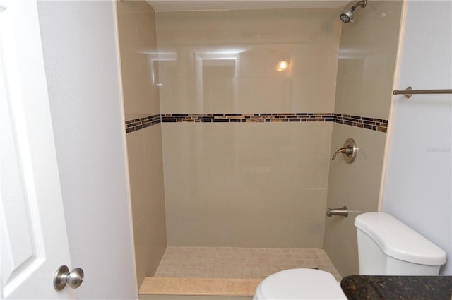 full bathroom featuring tiled shower and toilet