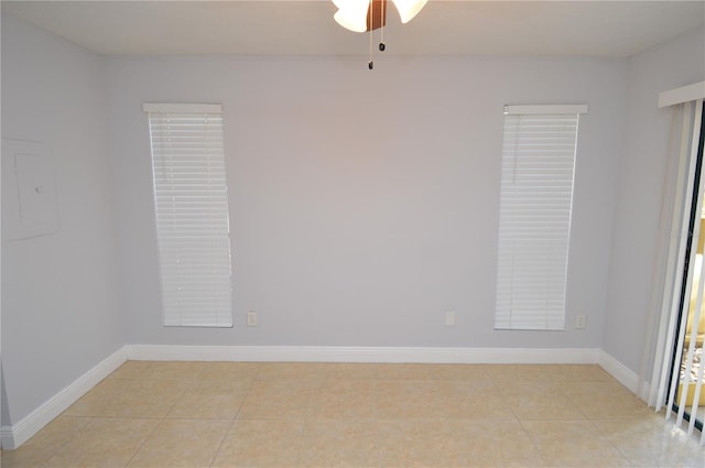 spare room featuring light tile patterned floors, baseboards, electric panel, and ceiling fan