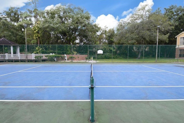 view of tennis court with community basketball court and fence