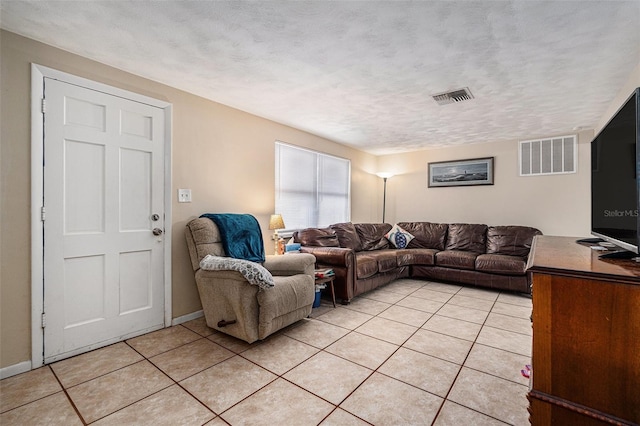 living area with visible vents, a textured ceiling, baseboards, and light tile patterned floors