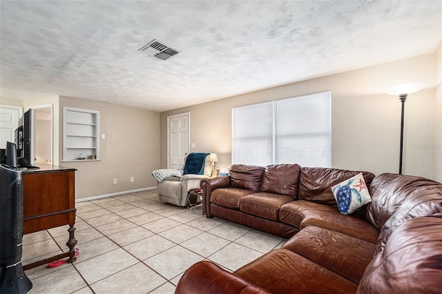 living room with built in features, visible vents, light tile patterned flooring, a textured ceiling, and baseboards