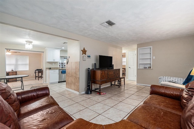 living room with visible vents, a textured ceiling, baseboards, and light tile patterned floors