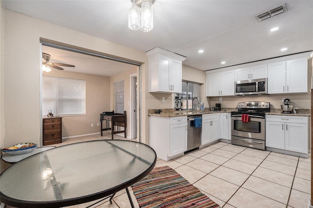 kitchen with light tile patterned flooring, visible vents, white cabinetry, appliances with stainless steel finishes, and light stone countertops